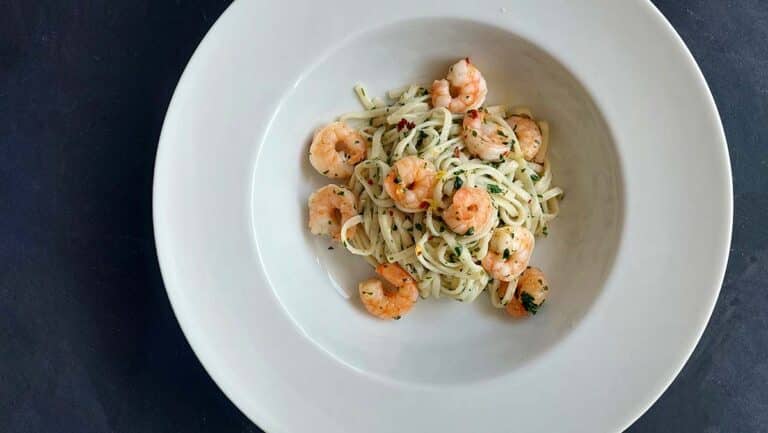 Krevety s těstovinami aglio olio na talíři s petrželkou a citronem