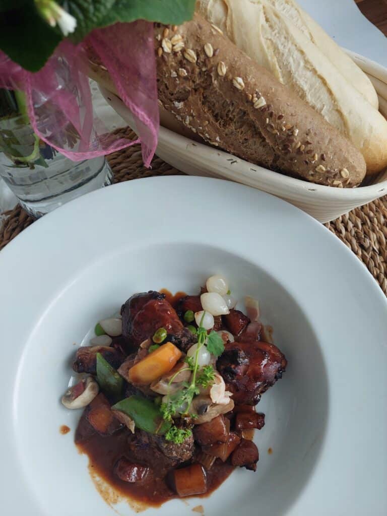 Kohout na víně (coq au vin) podávaný v hlubokém talíři