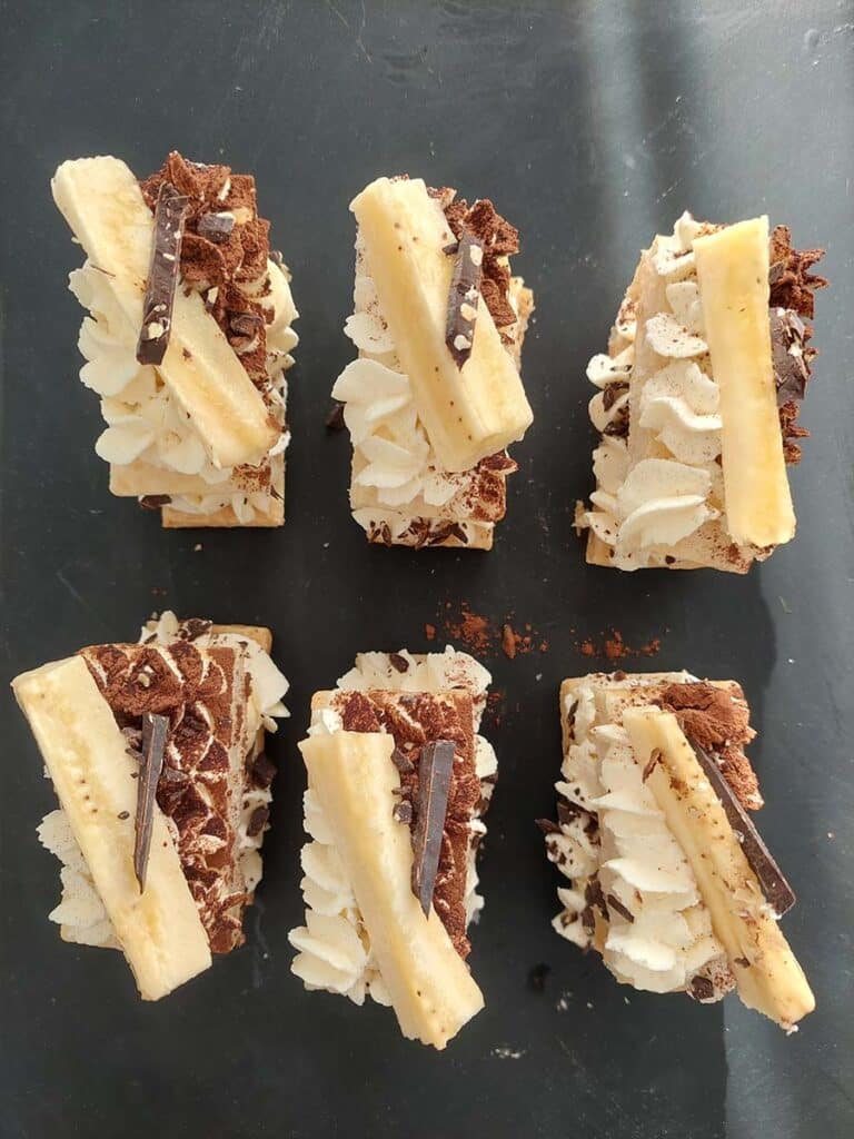 Mille-feuille s banánem a čokoládou ozdobený krémem a hoblinkami čokolády